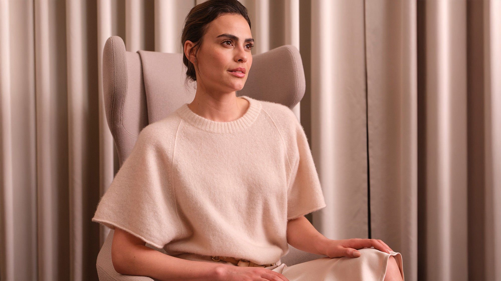 Eine braunhaarige Frau sitzt auf einem bequem Sessel.