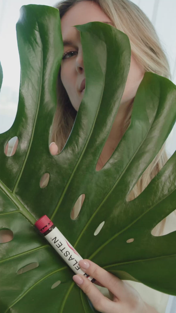 Eine blonde Frau zeigt eine ELASTEN® Trinkampulle in die Kamera in trinkt diese