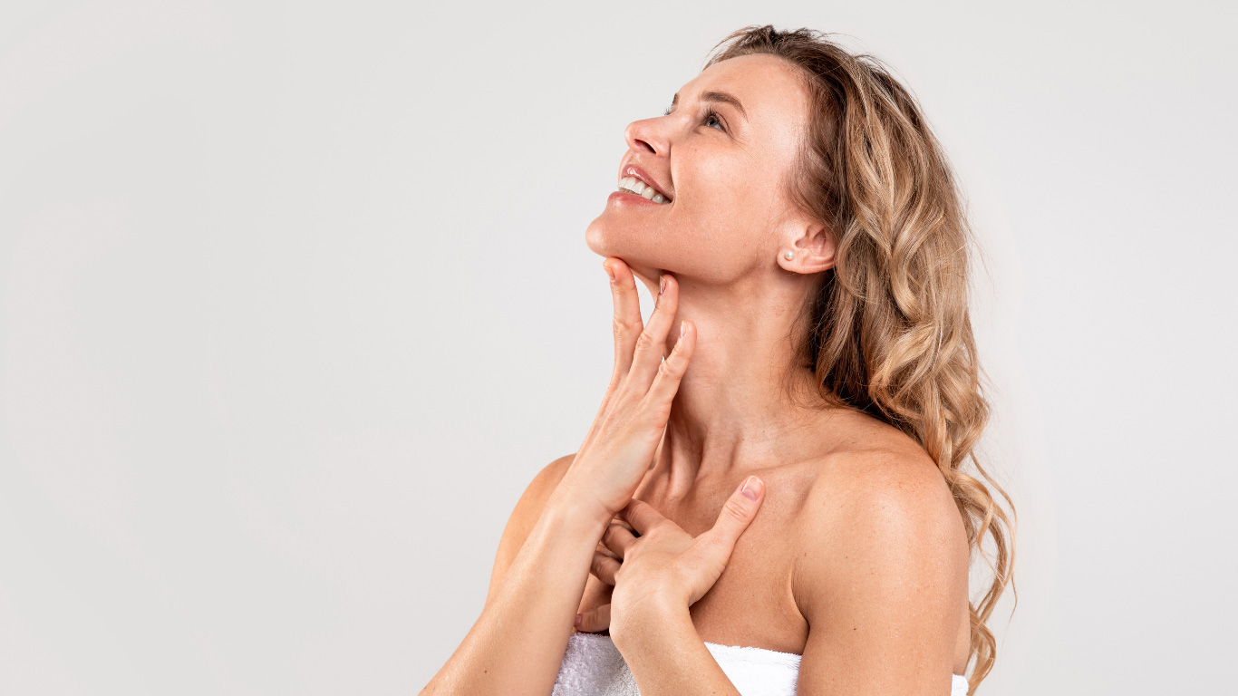 Frau mit gesunder, normaler Haut lächelt und berührt sanft ihren Hals